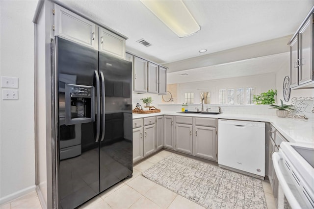 kitchen with gray cabinets, white appliances, visible vents, and a sink