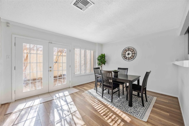 dining area with a textured ceiling, french doors, wood finished floors, and visible vents