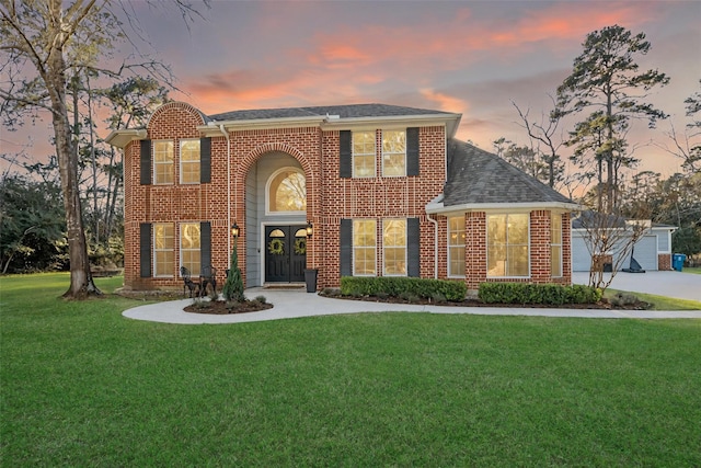 view of front of house featuring brick siding, a front lawn, and roof with shingles