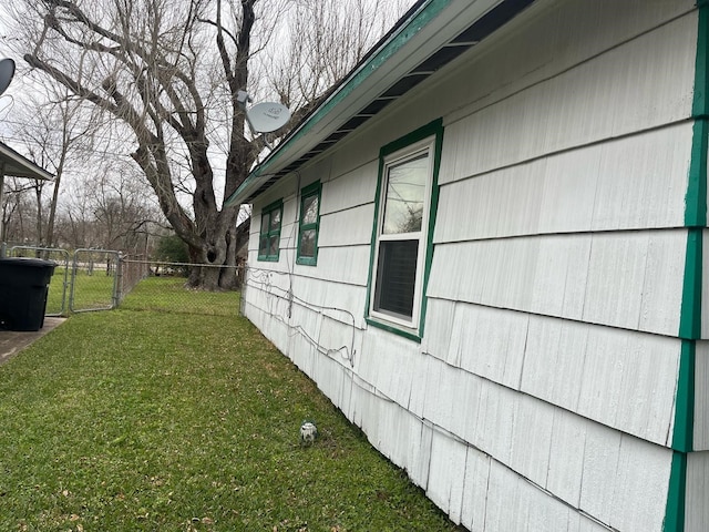 view of side of home with a lawn, fence, and a gate