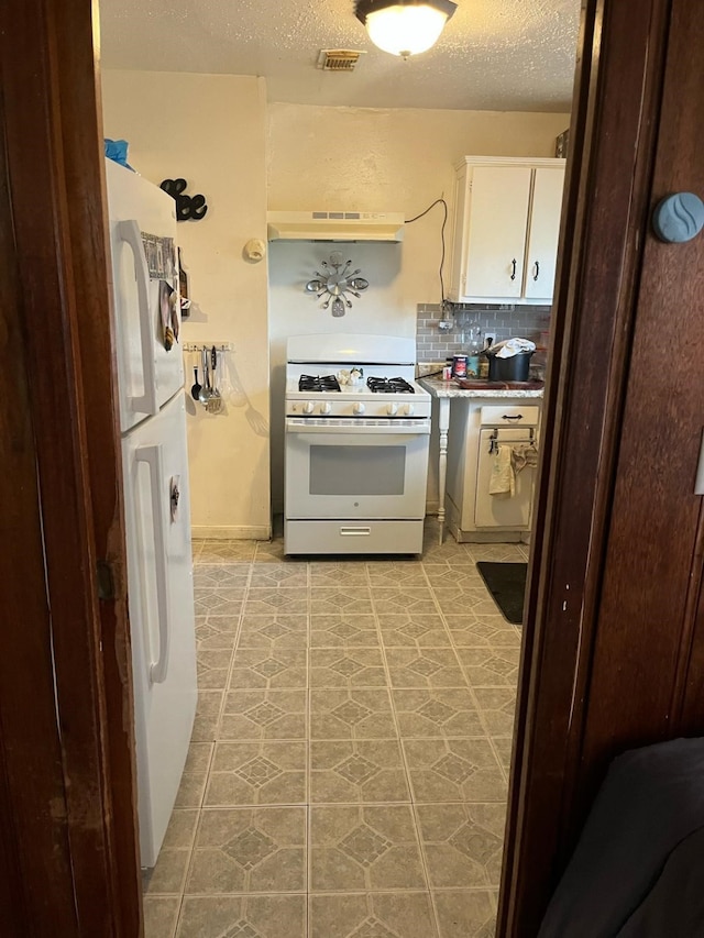 kitchen featuring visible vents, backsplash, a textured ceiling, white appliances, and under cabinet range hood