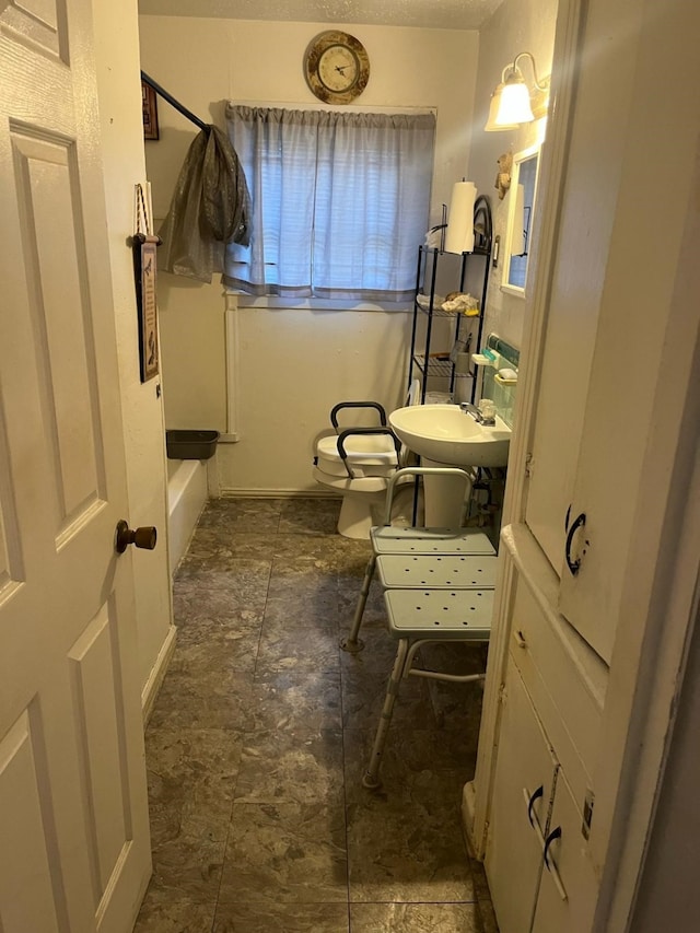 bathroom with stone finish floor, a sink, and toilet