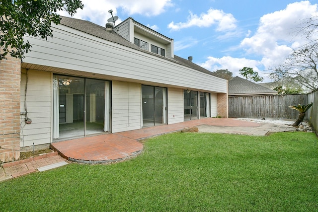 rear view of house with a patio area, a shingled roof, fence, and a yard