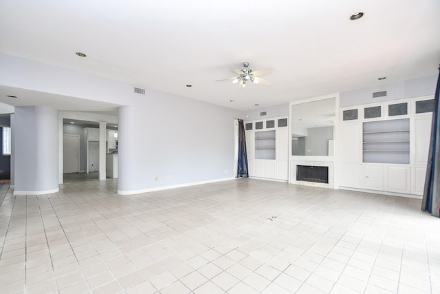 unfurnished living room featuring ceiling fan, built in shelves, a fireplace, visible vents, and baseboards