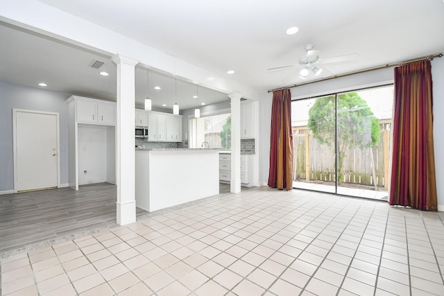 unfurnished living room featuring light tile patterned floors, decorative columns, visible vents, and a ceiling fan