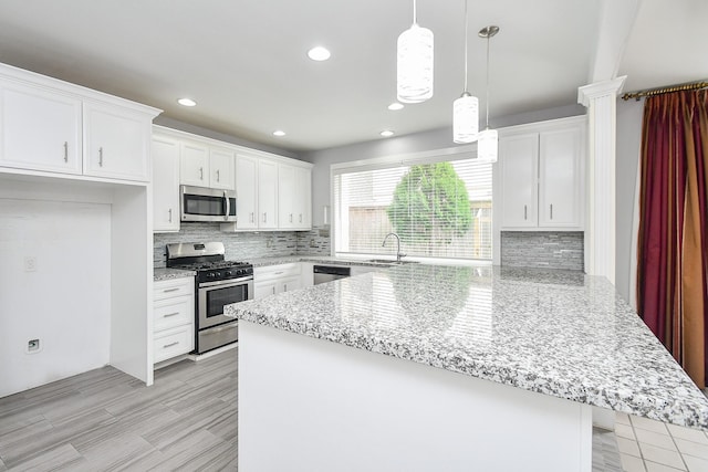 kitchen featuring stainless steel appliances, a peninsula, backsplash, and white cabinets