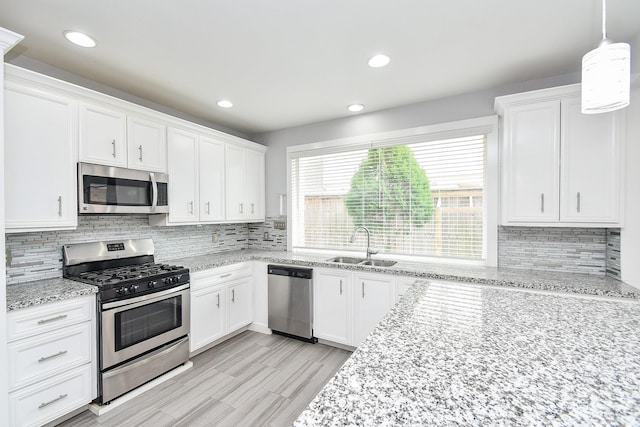 kitchen featuring tasteful backsplash, appliances with stainless steel finishes, a sink, and white cabinets