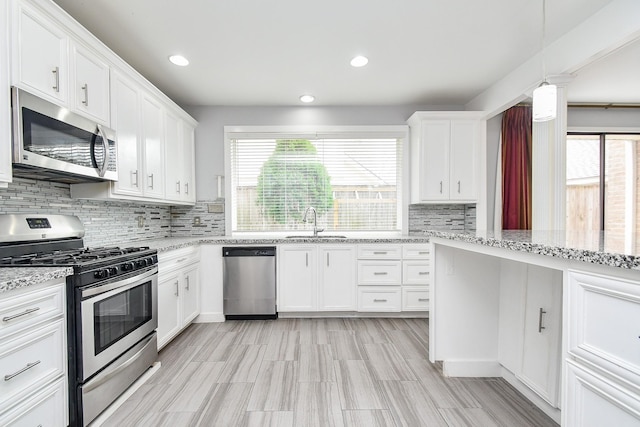 kitchen with decorative backsplash, appliances with stainless steel finishes, white cabinets, and a sink