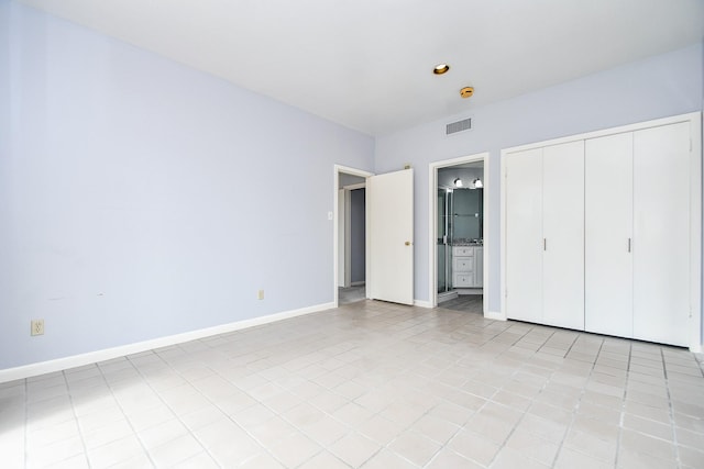 unfurnished bedroom featuring a closet, visible vents, baseboards, and ensuite bathroom