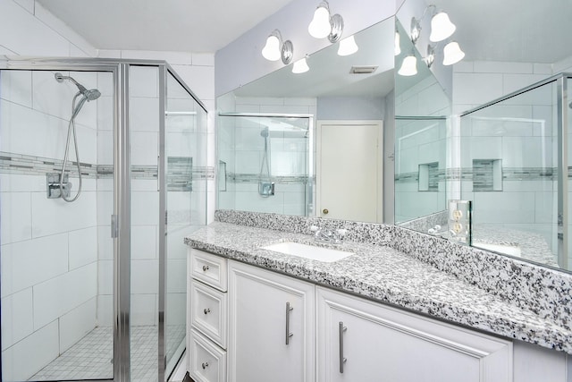 full bath with visible vents, a shower stall, and vanity