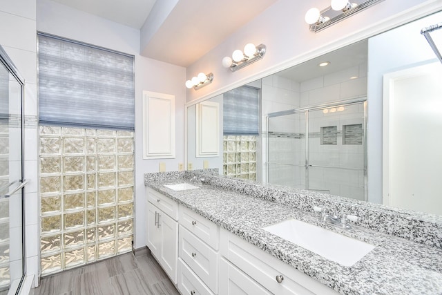 full bath featuring double vanity, a stall shower, and a sink