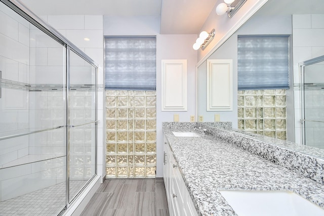 bathroom featuring double vanity, a stall shower, and a sink