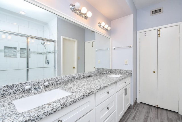 full bathroom with double vanity, a shower stall, visible vents, and a sink