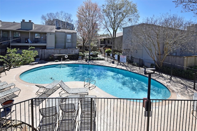 pool with a patio area, stairs, and fence