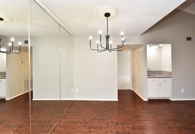 unfurnished dining area with dark wood-type flooring, a sink, visible vents, and an inviting chandelier