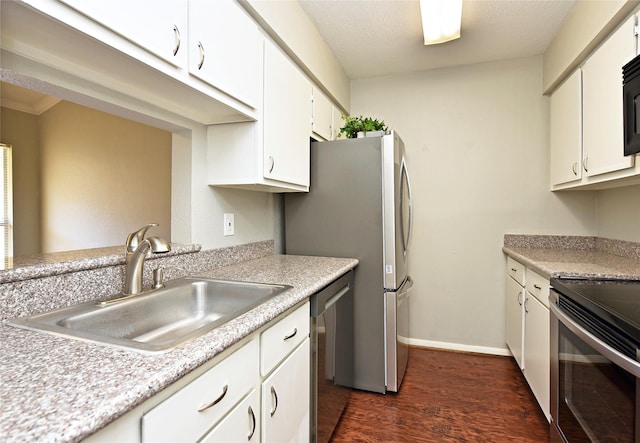 kitchen with dark wood finished floors, light countertops, appliances with stainless steel finishes, white cabinetry, and a sink