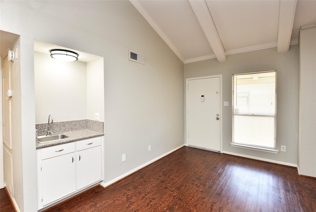 kitchen with vaulted ceiling with beams, dark wood finished floors, white cabinets, a sink, and baseboards