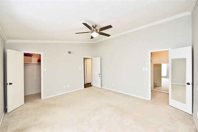 unfurnished bedroom with a walk in closet, light colored carpet, crown molding, and baseboards