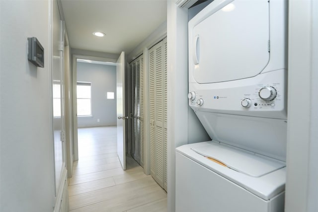 laundry room featuring laundry area, light wood-style floors, stacked washing maching and dryer, and recessed lighting