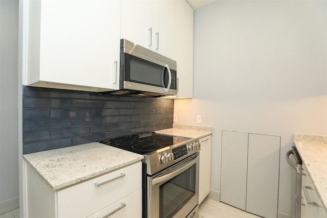 kitchen with stainless steel appliances, light stone countertops, white cabinets, and tasteful backsplash