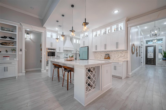 kitchen with crown molding, light wood finished floors, custom exhaust hood, double oven, and fridge