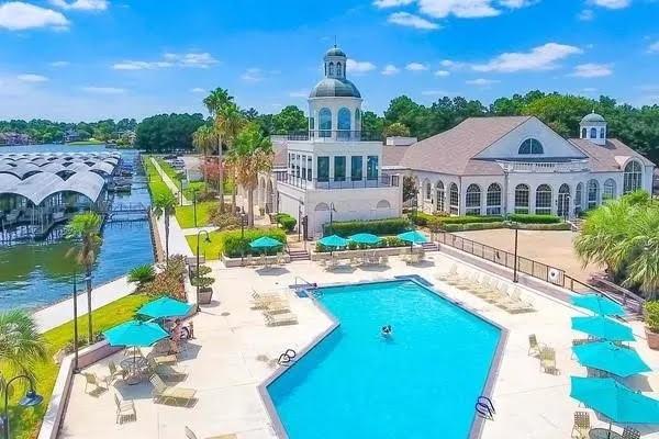 community pool featuring a patio, a water view, and fence