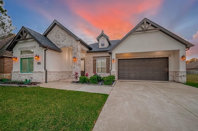 view of front of house with an attached garage, brick siding, driveway, stucco siding, and a front lawn