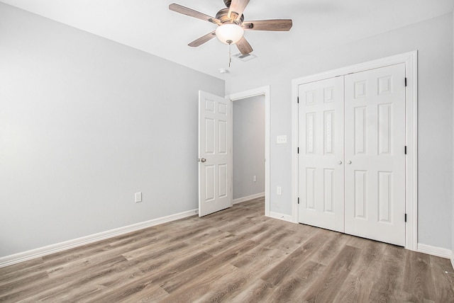 unfurnished bedroom with baseboards, visible vents, ceiling fan, wood finished floors, and a closet