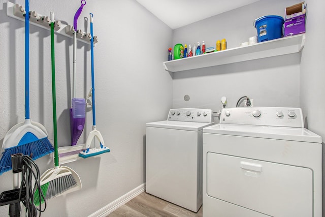 clothes washing area with laundry area, baseboards, washer and clothes dryer, and light wood finished floors