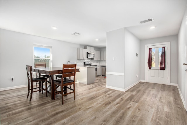 dining area featuring light wood finished floors, recessed lighting, visible vents, and baseboards