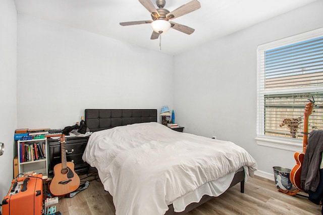 bedroom featuring multiple windows, ceiling fan, baseboards, and wood finished floors