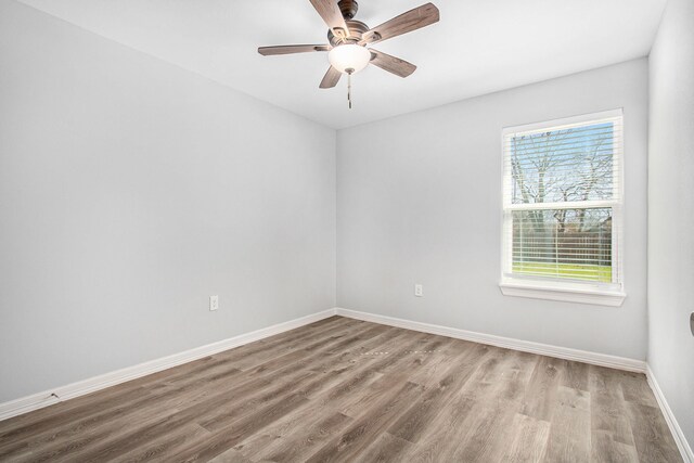 empty room with wood finished floors, a ceiling fan, and baseboards