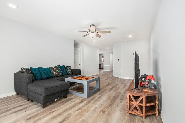 living area with light wood-type flooring, baseboards, a ceiling fan, and recessed lighting