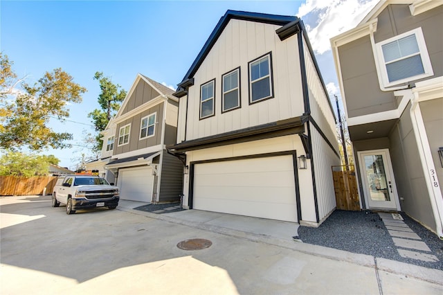 view of property with concrete driveway, board and batten siding, an attached garage, and fence