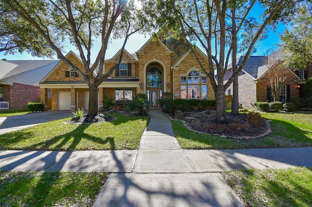 traditional-style house with brick siding, aphalt driveway, and a front yard