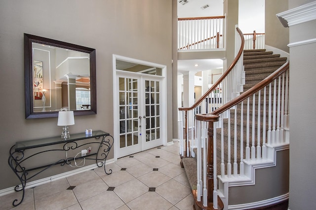 entryway featuring decorative columns, visible vents, tile patterned floors, a high ceiling, and french doors