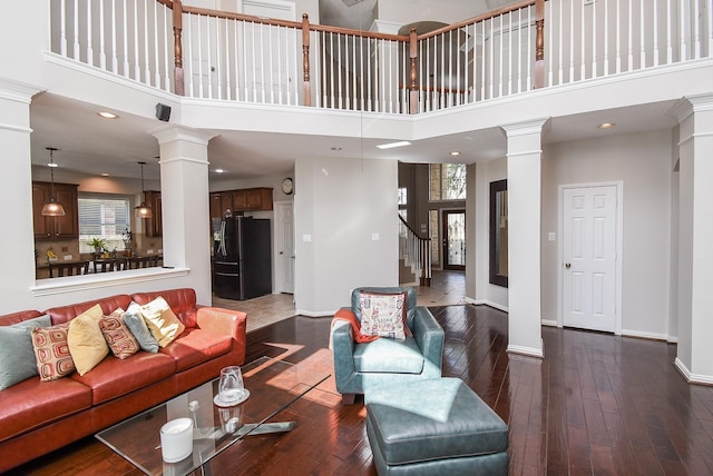 living room featuring a healthy amount of sunlight, dark wood-style flooring, and ornate columns