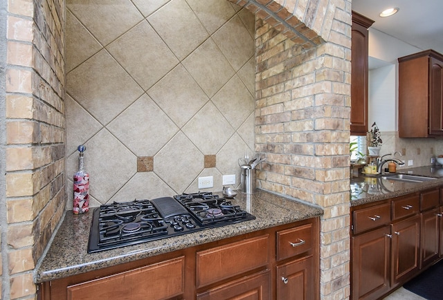 kitchen featuring black gas cooktop, recessed lighting, decorative backsplash, a sink, and dark stone counters