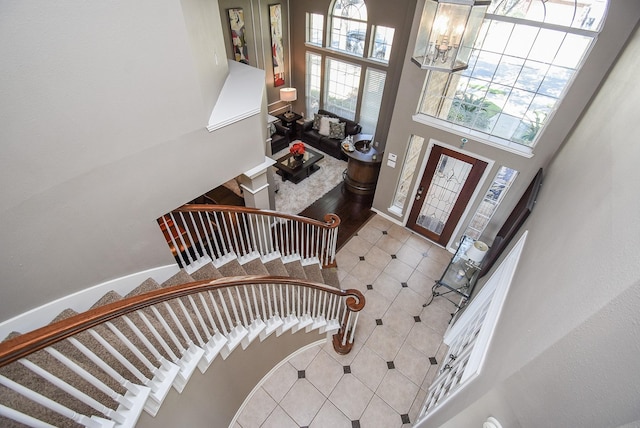 foyer entrance with stairs, a chandelier, a towering ceiling, and tile patterned floors