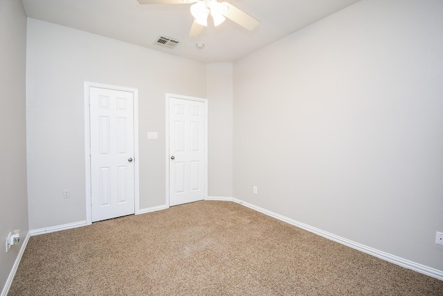 carpeted empty room with baseboards, visible vents, and ceiling fan