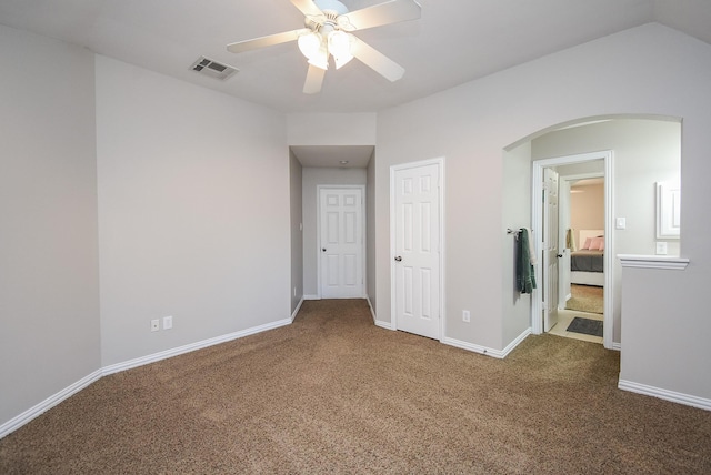 unfurnished bedroom with visible vents, arched walkways, baseboards, lofted ceiling, and carpet