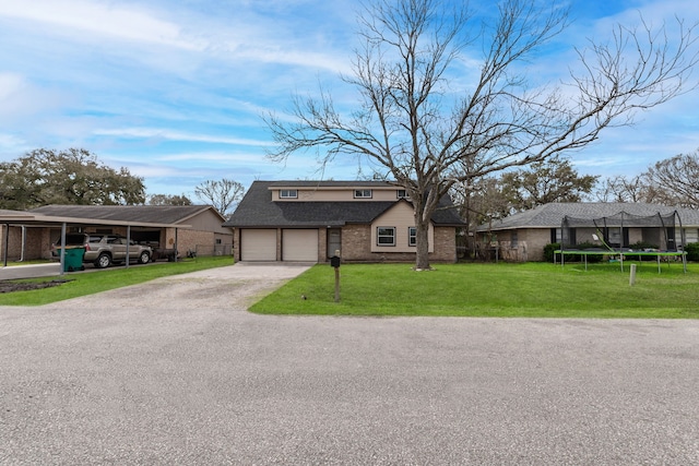 view of front of property featuring brick siding, a shingled roof, driveway, a trampoline, and a front yard