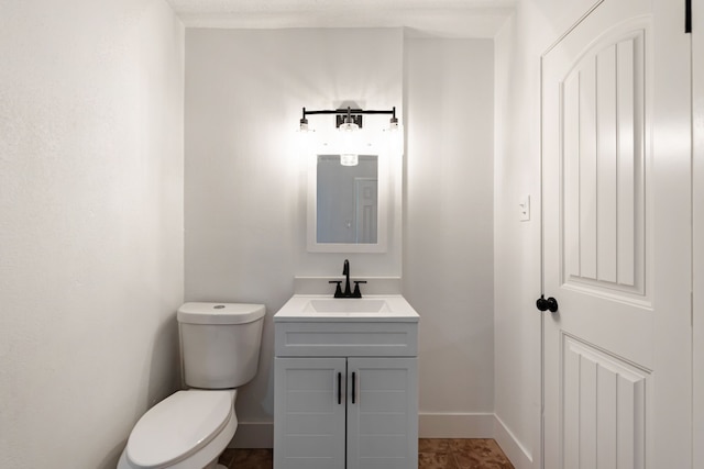 bathroom with baseboards, vanity, and toilet