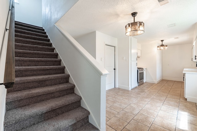 stairs with tile patterned flooring, visible vents, baseboards, and a textured ceiling