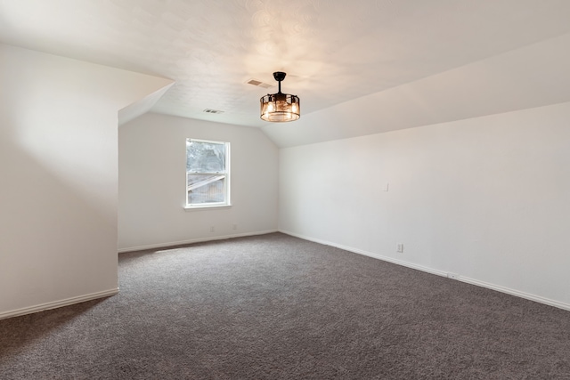 bonus room with dark carpet, baseboards, visible vents, and vaulted ceiling