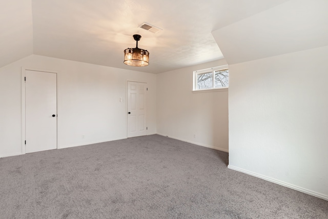 spare room featuring baseboards, visible vents, vaulted ceiling, and carpet flooring