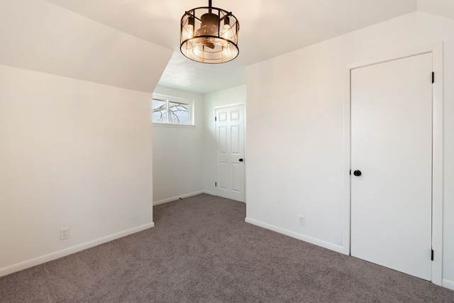 empty room with baseboards, vaulted ceiling, and carpet flooring