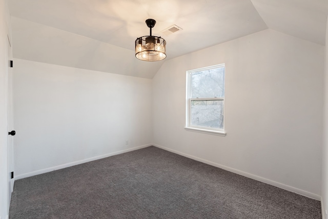 spare room featuring lofted ceiling, dark carpet, visible vents, and baseboards