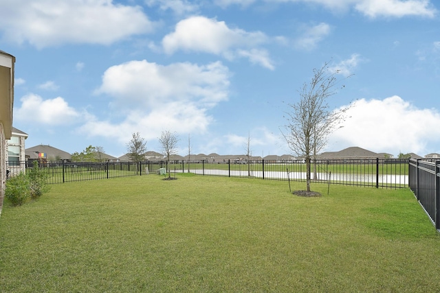 view of yard with a fenced backyard and a water view