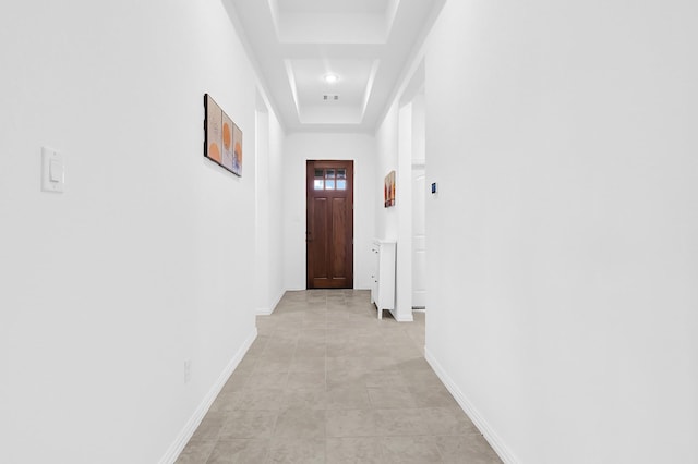 corridor featuring a tray ceiling and baseboards